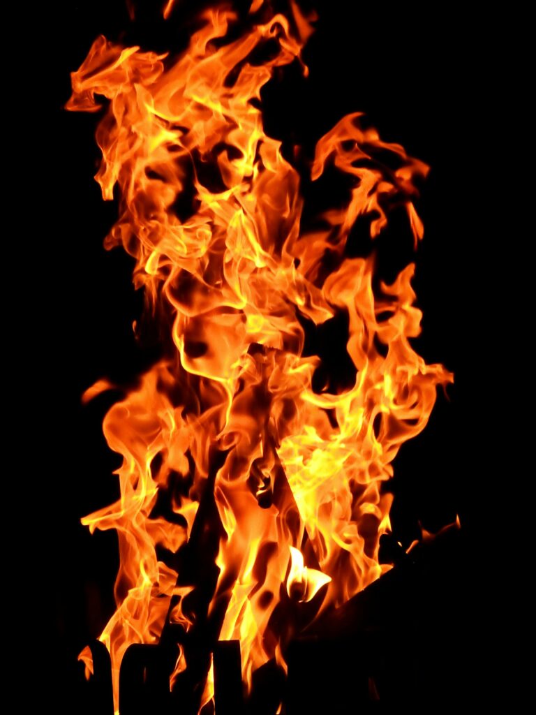 Close-up fiery blaze with vibrant orange flames creating a dynamic pattern against a dark backdrop.